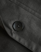 Close-up of MAYED black herringbone fabric and button detail.