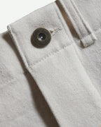 Close-up of MAYED women’s ecru Candiani denim trousers, showing waistband, belt loop and metal button detail.